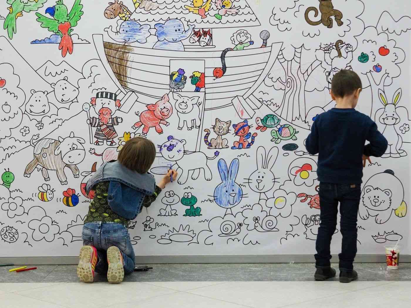 Два мальчика раскрашивают стену с обоями-раскрасками